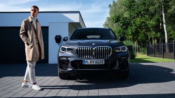 Híbrido enchufable BMW X5 xDrive45e G05 vista del frontal delante de un garaje Híbrido enchufable BMW X5 xDrive45e G05 vista del frontal delante de un garaje con modelo