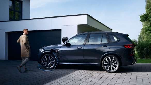 Híbrido enchufable BMW X5 xDrive45e G05 vista del lateral delante de un garaje Híbrido enchufable BMW X5 xDrive45e G05 vista del lateral delante de un garaje con modelo