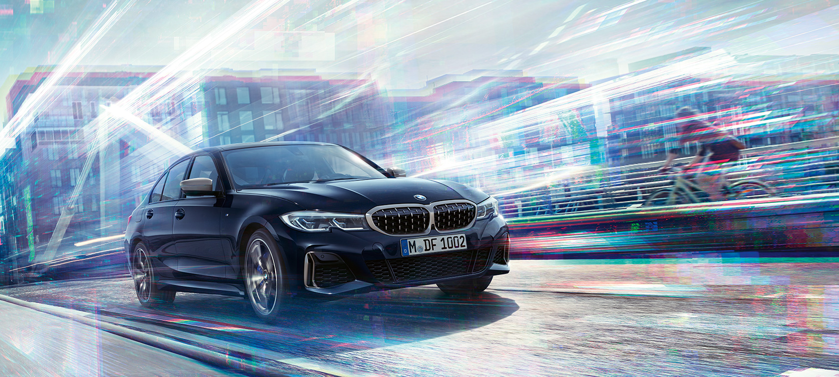 BMW Serie 3 Sedán, BMW M340i xDrive. Vista lateral de tres cuartos del BMW M340i xDrive en movimiento en el camino frente a un fondo urbano.