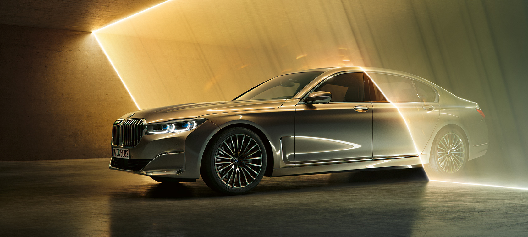 BMW Serie 7 en vista de tres cuartos del frontal BMW Serie 7: BMW gris, en vista de tres cuartos del frontal, rodeado de rayos de luz
