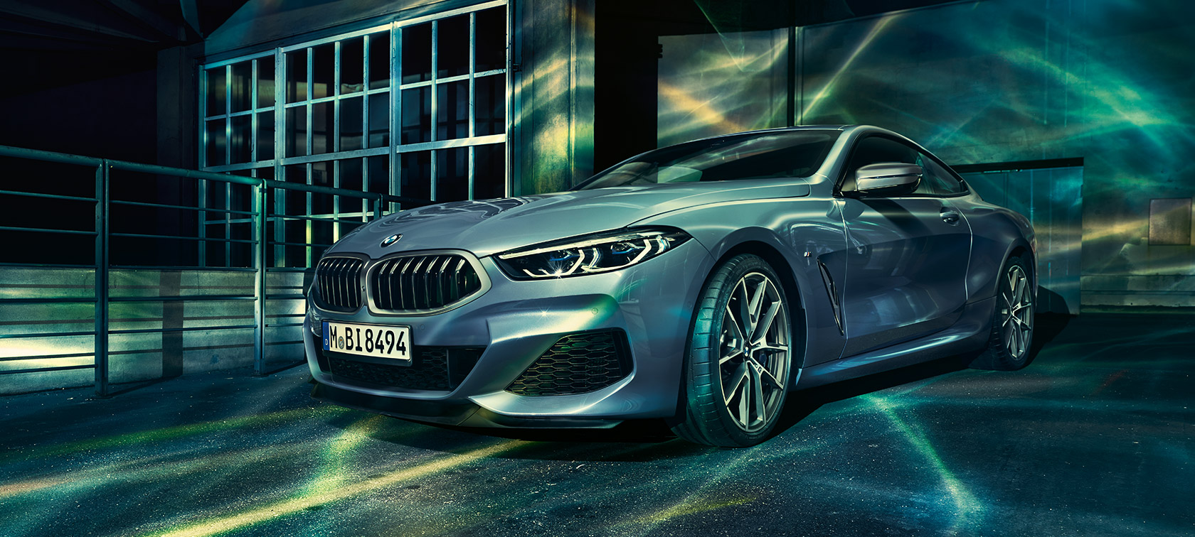 El BMW Serie 8 Coupé, toma delantera de tres cuartos. El BMW Serie 8 Coupé, vista delantera de tres cuartos, frente a un edificio industrial.