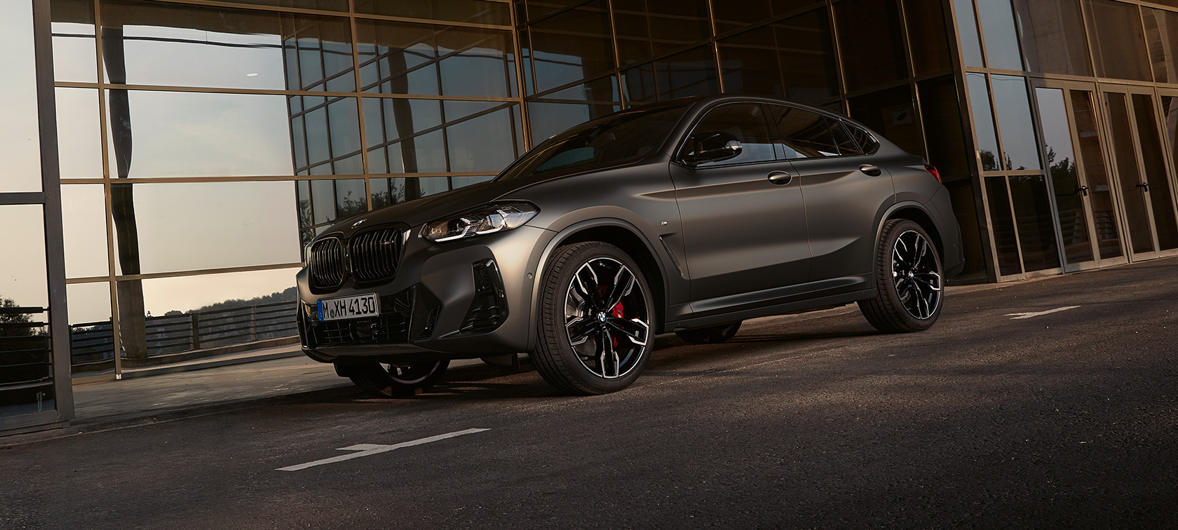 Vista de tres cuartos del frontal BMW X4 M40i G02 LCI 2021 Renovación BMW X4 M40i G02 LCI Renovación 2021 Vista de tres cuartos del frontal delante de fachada de cristal