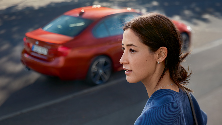 Asistencia de BMW en el Camino Mujer de perfil enfrente de un BMW