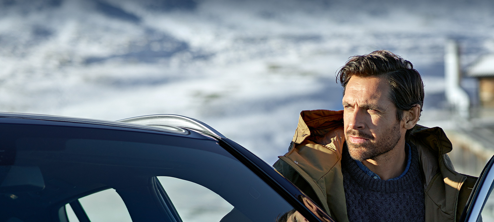 Accesorios BMW Originales y Servicios BMW para Otoño e Invierno Hombre con parka de invierno parado frente a la puerta de su BMW